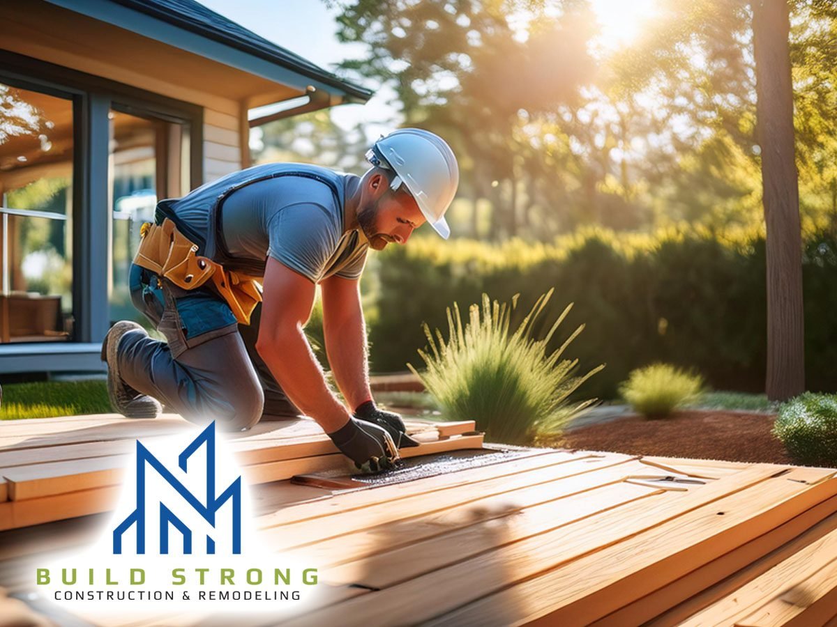male professional technician working performing expert construction of custom deck and patio outdoors in yard behind residential home