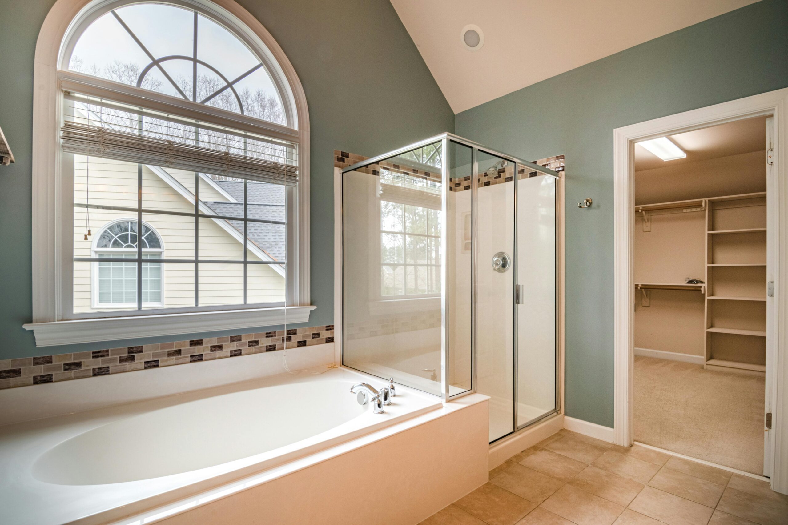 Spacious contemporary bathroom featuring a luxurious bathtub, shower, and adjacent walk-in closet.